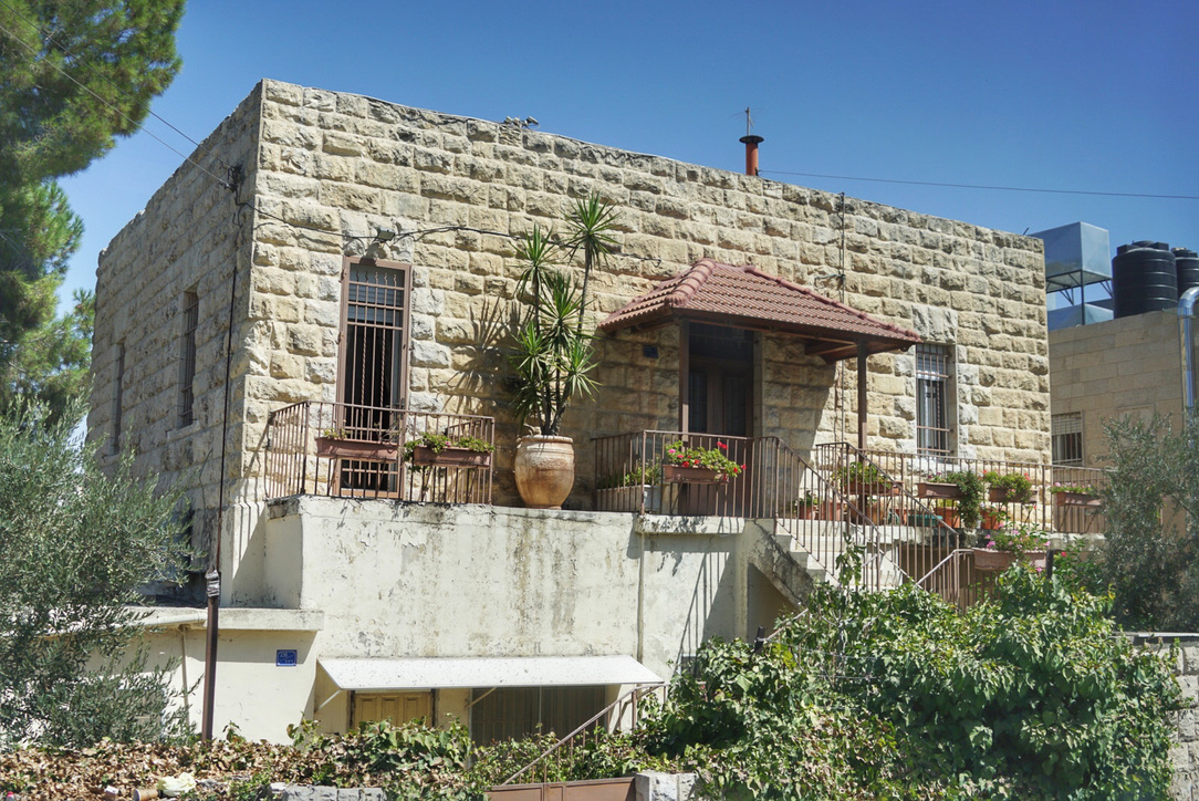 Helles Steinhaus mit Pflanzen und kleiner Terrasse