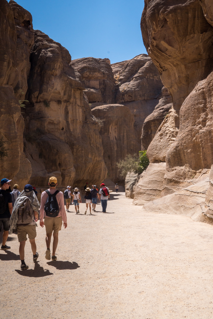 Besucher auf einem Weg zwischen hohen Felsen in Petra