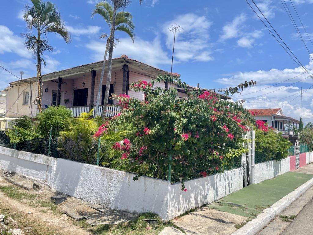 Veranda eines Hauses mit Palmen und blühenden Sträuchern auf Kuba