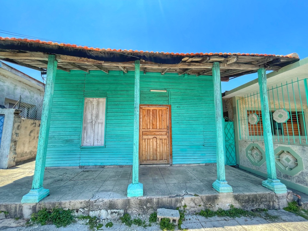 Türkisfarbenes Holzhaus mit Veranda und brauner Eingangstür auf Kuba
