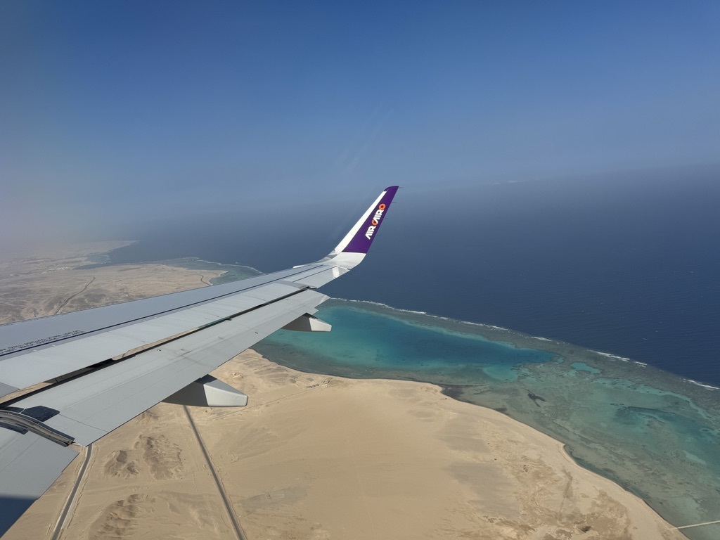 Blick aus einem Air-Cairo-Flugzeug auf die Wüstenküste und das türkisfarbene Rote Meer