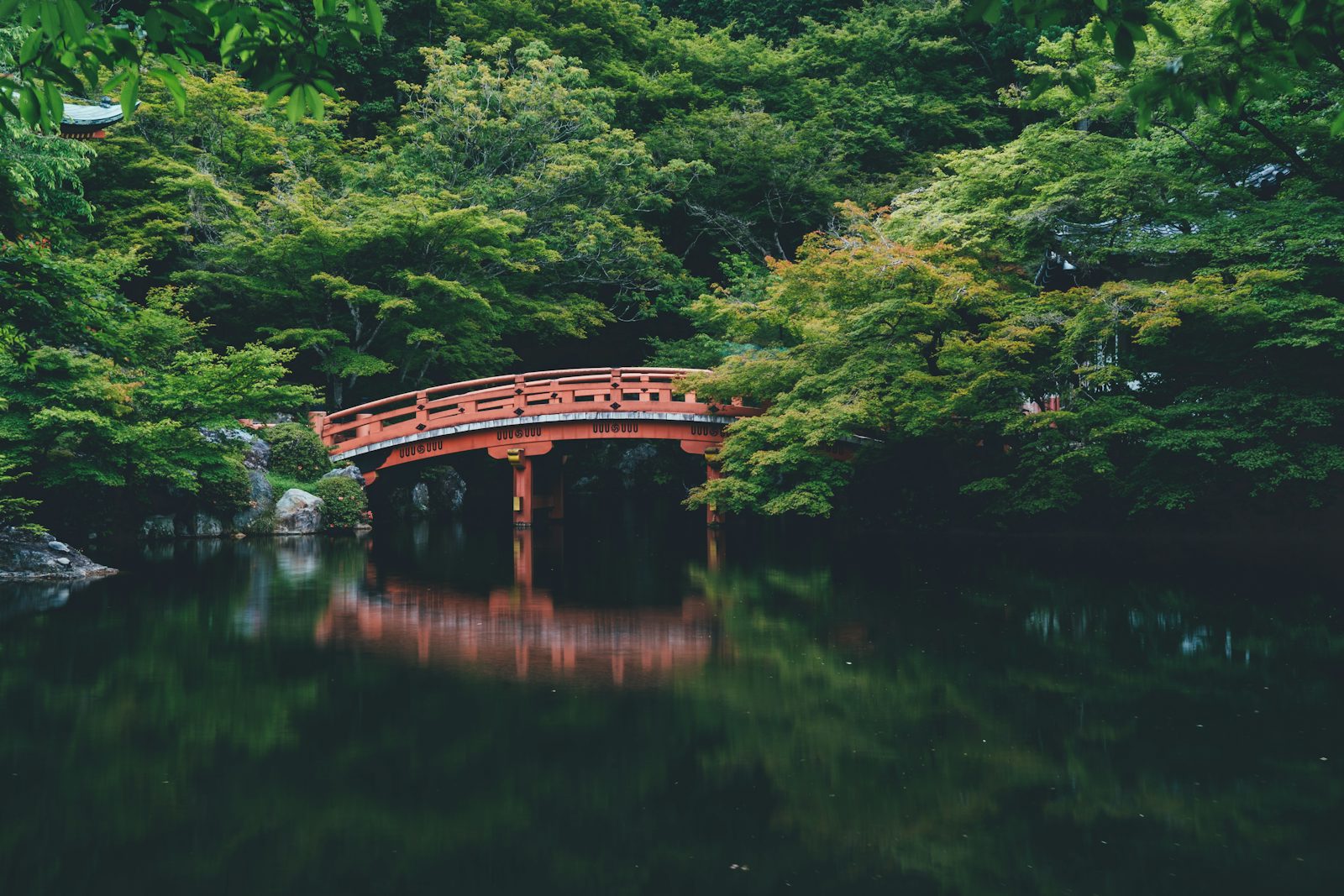 Rote Brücke in einer grünen Gartenlandschaft Kyotos