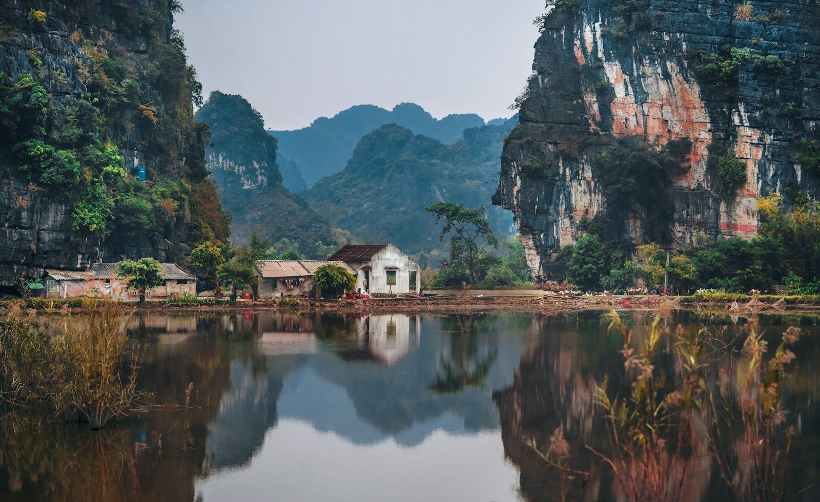 Häuser am Wasser zwischen Kalksteinfelsen bei Ninh Binh